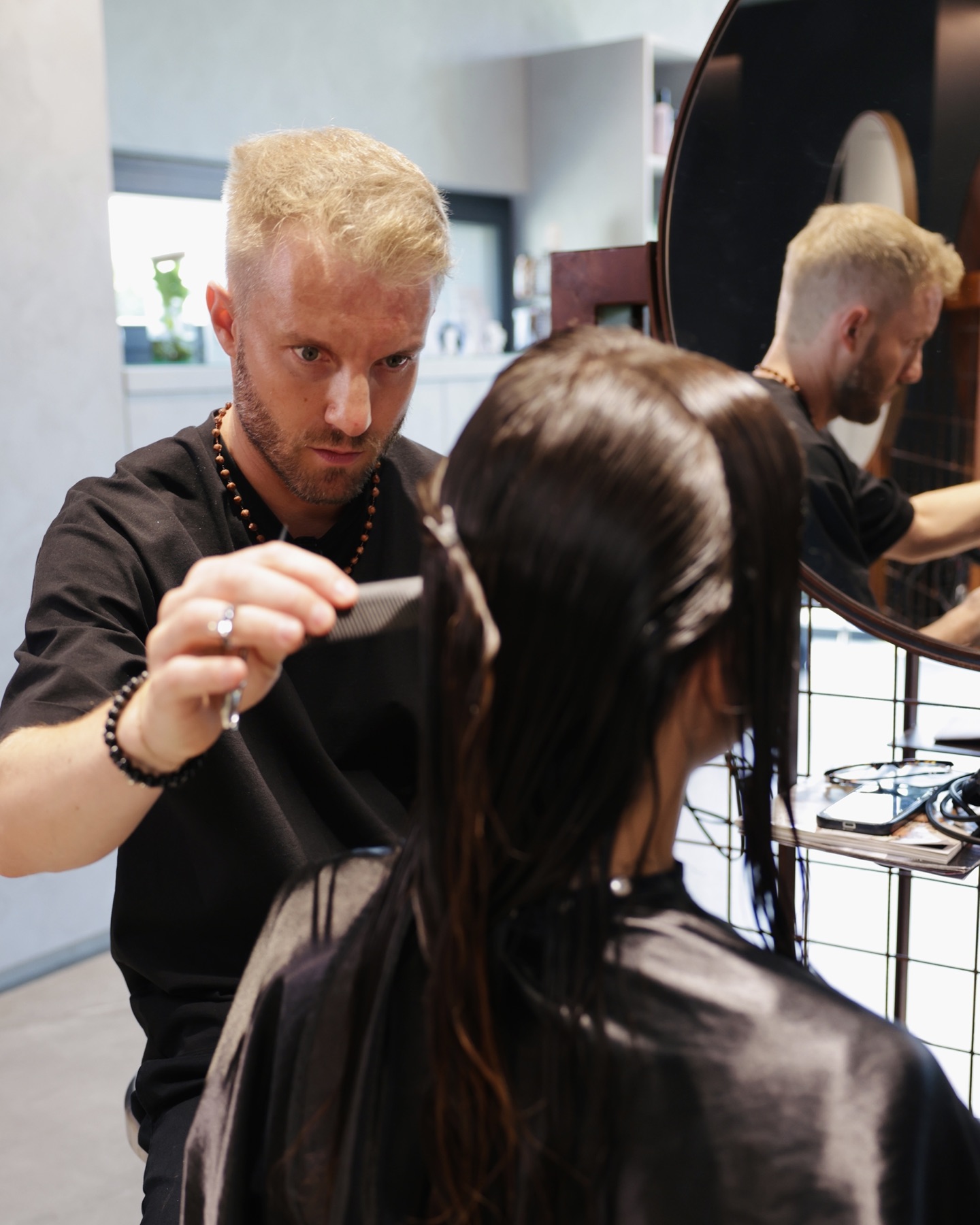 Marco Ambrosi con pettine e forbici mentre lavora su una cliente nel salone